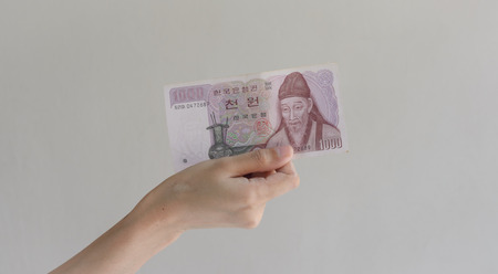 woman Hand holding korean money won on wall backgroundの写真素材