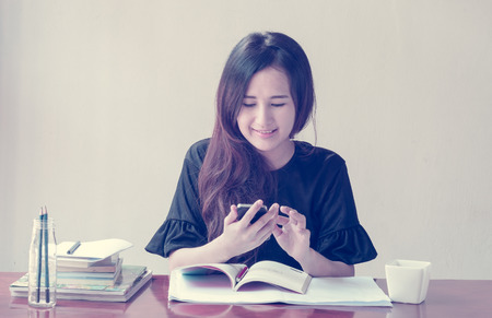 asian Woman is working and use a mobile phonewith retro filterの写真素材