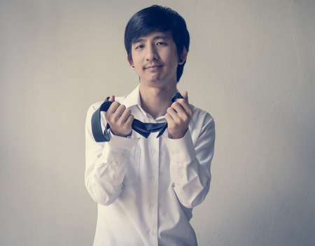 asia businessman adjusts a tie against with retro filterの写真素材