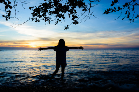 silhouette happy woman the sunset on the beach in thailandの写真素材