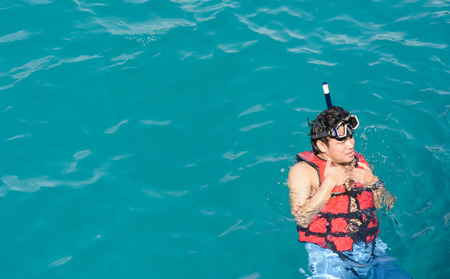 man swimming in life jacket on the natural sea at koh chang, Thailandの写真素材