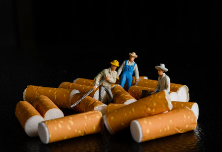 lot of cigarette butt with miniatures workers on black