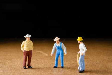 miniature figures of  male workers talking on wood pattern with selective focusの写真素材