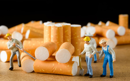 cigarette butt with miniatures workers on wood with selective focusの写真素材