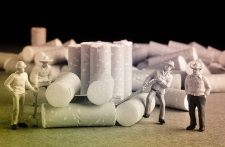 cigarette butt with miniatures workers on wood with retro filterの写真素材