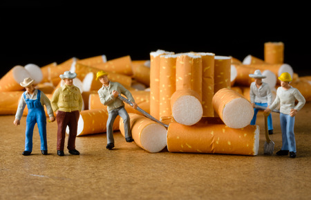 cigarette butt with miniatures workers on wood with selective focusの写真素材