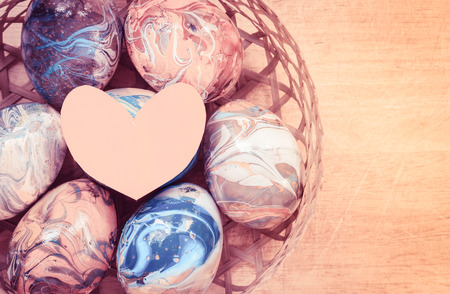 close up Easter eggs in basket with heart paper shape and retro filterの写真素材