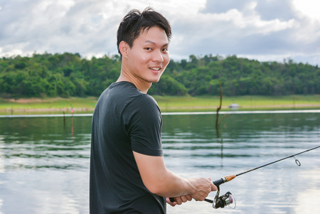 man fishing with rod on water natural dam at outdoor (asia man)の写真素材