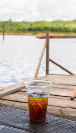 Cola ice Drink with on a wood raft home on natural riverの写真素材