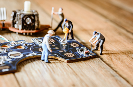 Electronic board with miniature figure worker man at repair and work. Selective focus with vintage filterの写真素材