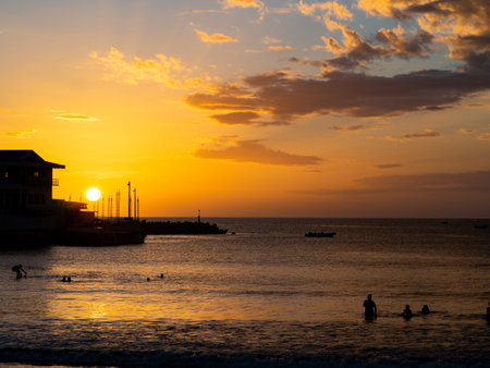 People enjoying the beautiful orange sunset next to the port of San Juan del Sur, pacific coast of Nicaraguaの写真素材