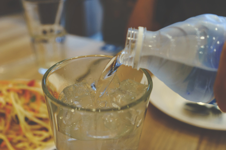 Pouring water into glass tableの写真素材