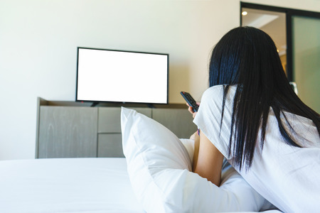Asia woman relax on bed and watching televisionの写真素材
