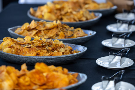 Close up of a lot of crispy chips in metal bowls on table
