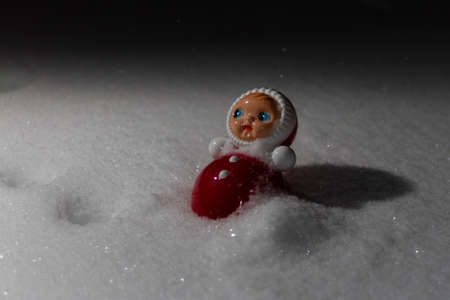 Scared red doll with a blue eyes in a snow
