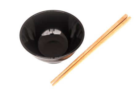 Black ceramic bowl with wooden shopsticks isolated on white backgroundの写真素材