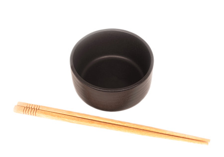 Black ceramic bowl with wooden shopsticks isolated on white backgroundの写真素材