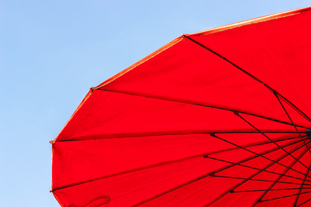 Old red umbrella with blue sky backgroundの写真素材