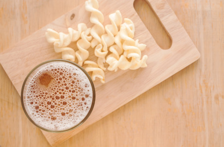 Glass of beer with potato on wooden backgroundの写真素材