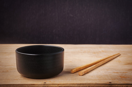 Still life black bowl with wooden shopsticks on dark wood backgroundの写真素材