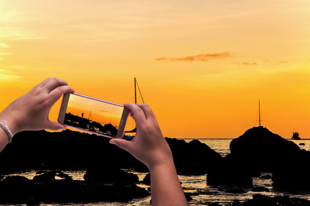 Image of shooting photographs with smartphone on seascapeの写真素材
