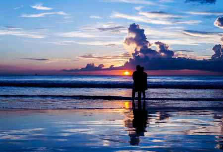 Emotion of love, Silhouette lovers relax on the beach in color of sunsetの写真素材