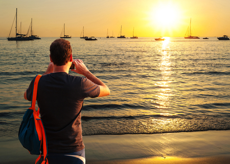 Some people shooting image with smart phone on beach sunset colorful in twilight over light the sunの写真素材
