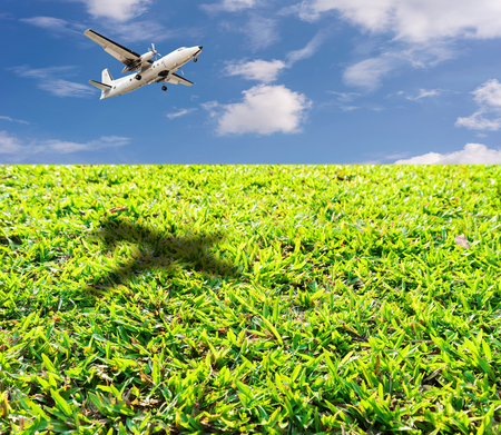 Green grass lawn with bright blue sky and airplane landingの写真素材