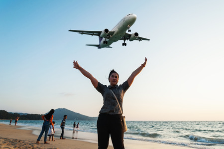 Phuket,Thailand - April 03, 2016: The women and some people relax on the beach sunset with airplane come in the land in twilightのeditorial素材