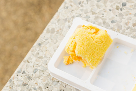 Sweet cake orange fruit in plastic white plate on marble chair at street side