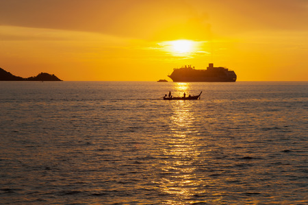 Dramatic sea and transport boat with color of sunset and over light the sun in twilightの写真素材