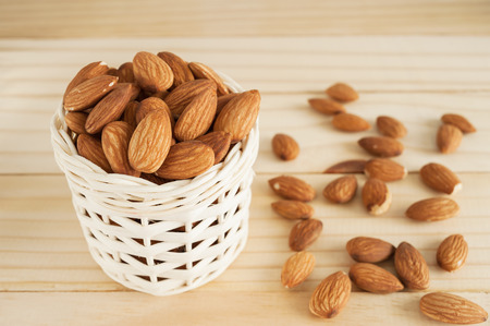 Almond in white basket on wooden tableの写真素材