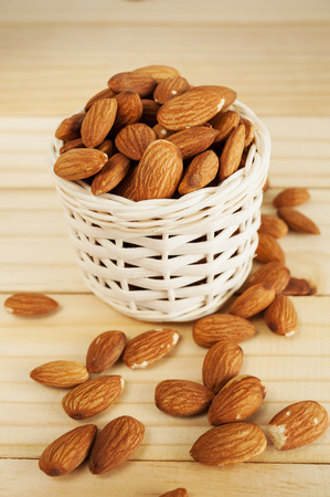 Almond in white basket on wooden tableの写真素材