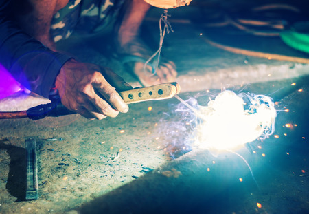 Hand of man welding steel blurred on black background, Welder concept filter color styleの写真素材