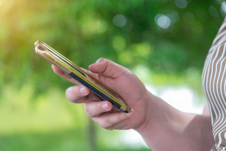 Online shopping and online banking and social network concept concept, Hand women with smart phone mobile on blurred bokeh nature backgroundの写真素材