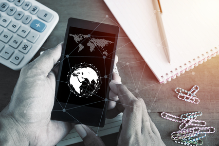 Social network and internet connection concept, Hand with smart phone mobile on desk with equipment wooden backgroundの写真素材