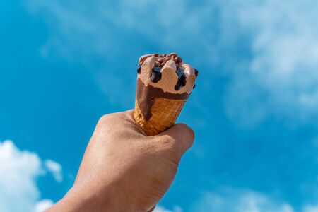 Hand with ice cream on blurred blue sky nature background, Relaxation concept