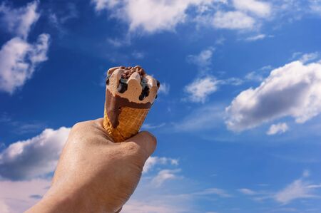 Hand with ice cream on blurred blue sky nature background, Relaxation conceptの写真素材