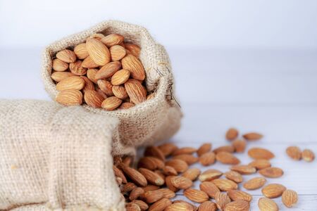 Almond in cloth bag on blurred white wooden tableの写真素材