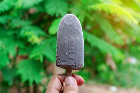 Hand with ice cream on blurred green nature background, Relaxation conceptの写真素材