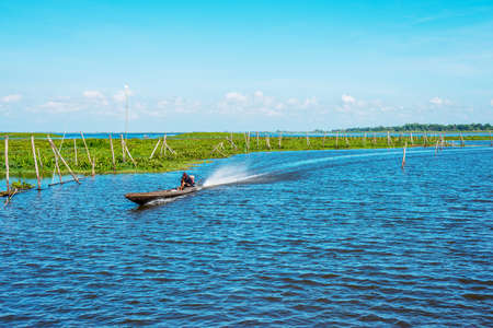 Pattalung, Thailand - March 07, 2020 : The image of a fisherman, sailing, to receive tourists, descend on a freshwater lake, in a soft sunny evening.のeditorial素材