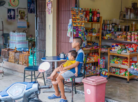 Nakhon si thammarat, Thailand - July 05, 2020 : Boy, who is raising a younger brother, and waiting for tourists, to come into service, in a small grocery store, in his shop.のeditorial素材
