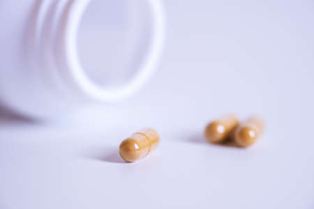 Pill spilling out of a bottle blurred background, Medicine capsule for health, Vitamin spilling out from bottle, Macroの写真素材