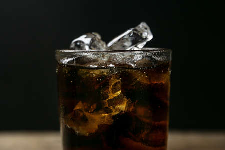 Solt drink being poures into a glass with ice on blurred shadow background