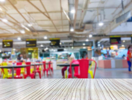 Wooden table top on blurred food court in shopping mall backgroundの写真素材