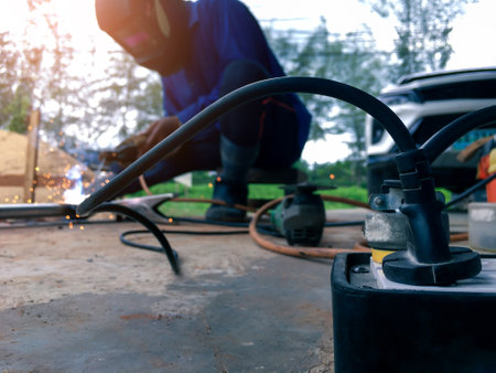 Close up power socket with a background of a worker welding metal for use in construction blurred...