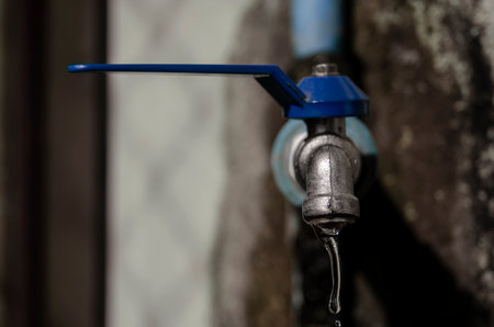 Wasting water - water drop from water tap, Leaky or tap, water tap in remote area, Deteriorated and dirty tap that everyone in the village uses to drink, which is located in a remote area It reflects the insufficiency of government agencies' water supply and the low quality of life of people in remote areasの素材 [FY310214392378]