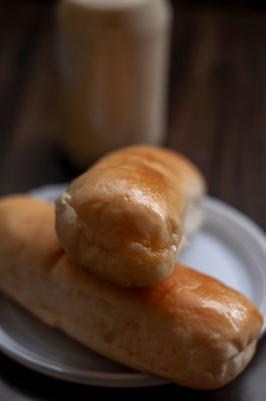 Bread on a white plate sits on a wooden board table with milk in a bottle behind it, Copy space,...