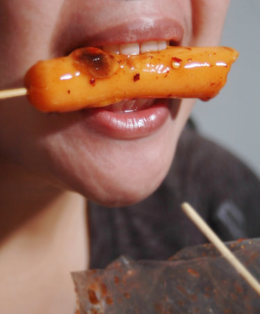 Woman eating sausage on blurred background, Street food coの写真素材