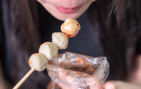 Woman happily eating meatball on gray blurred backgroundの写真素材